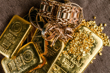 A pile of gold bars gold jewelry and gold granules on the background to the coarse texture of the...