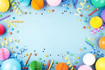 Birthday party background on blue. Top view. Frame made of colorful serpentine, balloons, candles,...