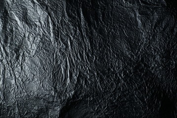 Thin wrinkled sheet of crushed tin aluminum silver foil background texture 