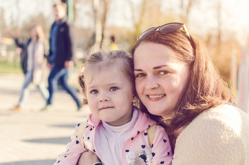 Fototapeta na wymiar Portrait of mom and her little daughter in the park in the sunlight