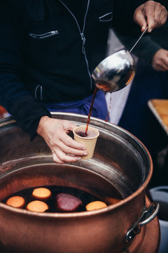 Pouring hot mulled wine, called Glühwein in German language, into a paper cup with a huge kitchen spoon. Favourite hot beverage at Christmas markets in Switzerland and in german-speaking countries. Ke