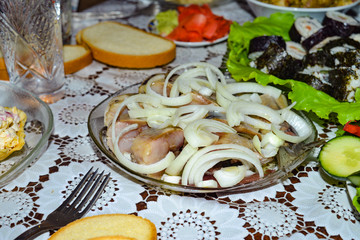 Marinated herring with onion cut into pieces in a plate poured with sunflower oil.