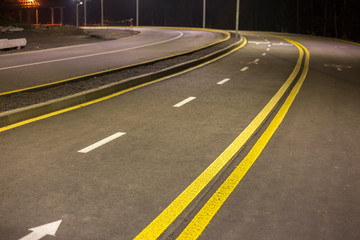 Wide modern smooth empty asphalt highway sharp turn sharp with bright white and double yellow...