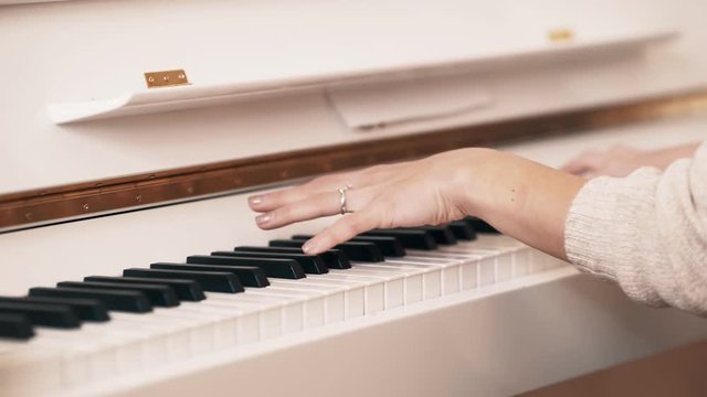 Play piano. Close up of female hands playing the piano. Fingers on the piano, vintage colors. A very close look at a jazz pianist's hands. Woman playing the white piano, close-up.