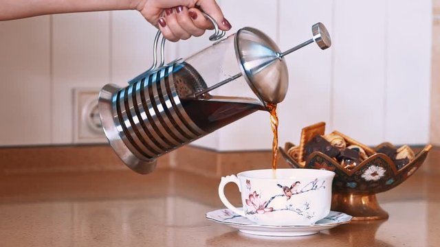 Pouring tea into cup from teapot