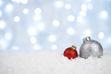 Silver and red Christmas balls on snow with defocused  lights
