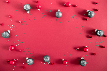 Christmas trendy composition. Frame made of fir tree branches, red and green decorations on red background. Christmas, New Year, winter concept. Flat lay, top view, copy space