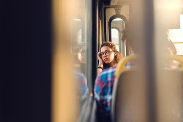 Thoughtful girl looking through window while sitting in public transportation.