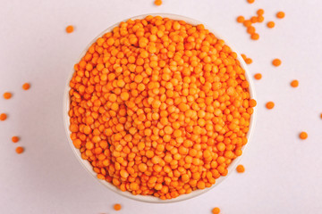 Raw red lentils in clay bowl on white marble background