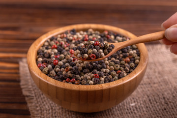 Mix of peppers in bowl burlap napkin on wooden background