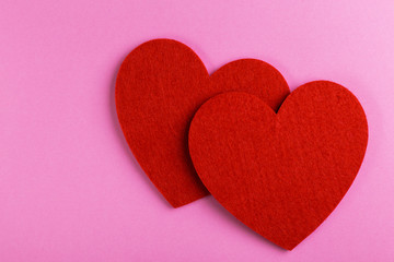 Two red felt heart on bright pink background