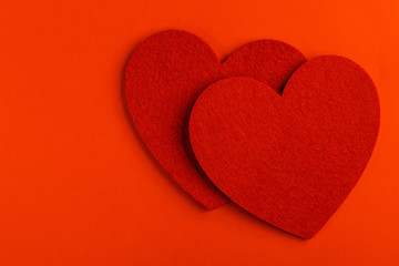 Two red felt heart on bright red background
