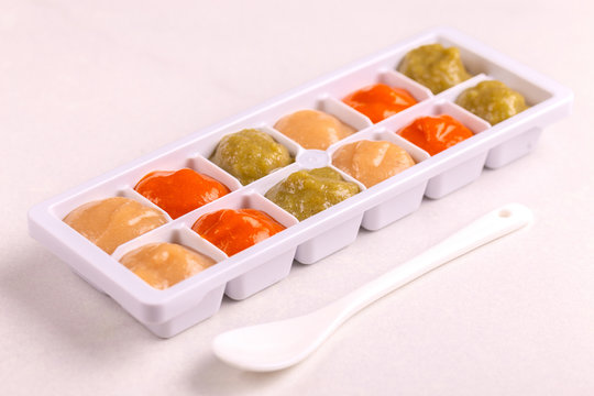 Multicolored pureed baby food in ice cube trays