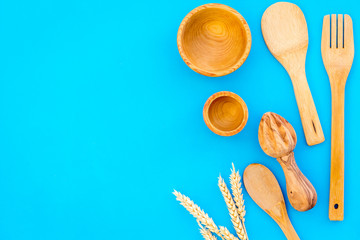 Fork, spoon, bowl in woodenware set on blue background top view space for text