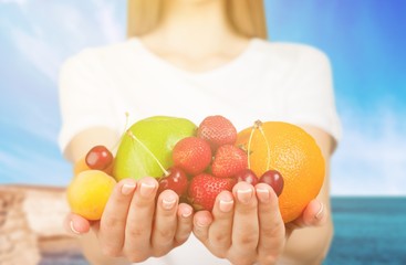 Young woman in white clothes holding fruits