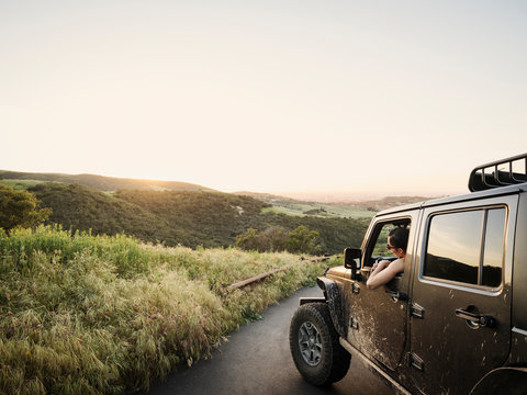 Woman In Off Road Vehicle Looking At Sunset