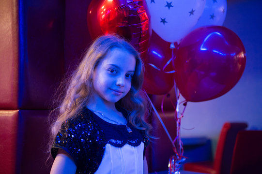 Girl cute smiling child hold bunch balloons lighted with blue light. Girl with balloons celebrate birthday in bowling club. Birthday party at bowling. Ideas how to celebrate birthday for teens