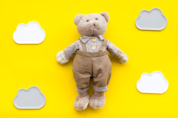 Handmade toys for newborn baby. Teddy bear. Yellow background top view