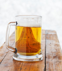 Glass mug with fresh beer on wooden bench