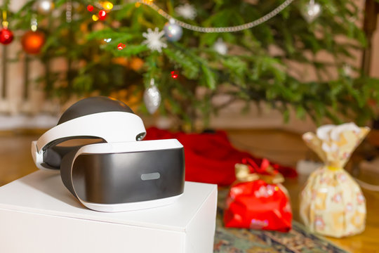 VR headset and other gifts under the Christmas tree with defocused lights in the background