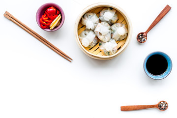 Dinner in Chinese restaurant with dim sum, sticks and tea on white background top view space for...