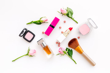 Makeup products for young girls. Composition with cosmetics with rose tones. Lipstick, bulk, eyeshadow, perfume, brushes and rose flowers on white background top view