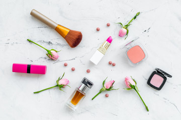 Fototapeta na wymiar Decorative cosmetics layout. Pink tones of lipstick, bulk, eyeshadow, perfume, brushes among rose flowers on white background top view