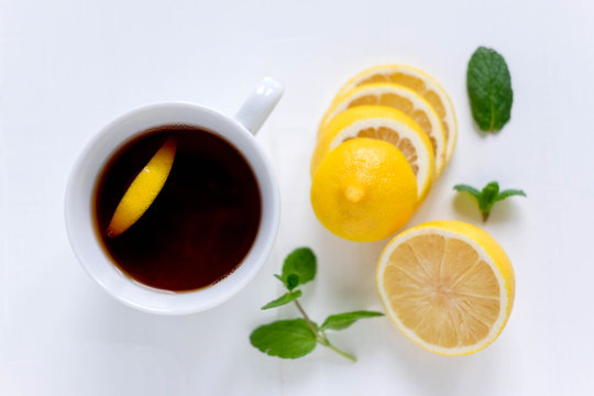 A cup of tea along with mint and lemon. Tea for colds. Natural cures for the disease. Vitamin C. Black tea with lemon on a white background