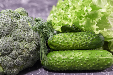 Fresh green vegetables variety on grey background. green salad, broccoli, cucumber.