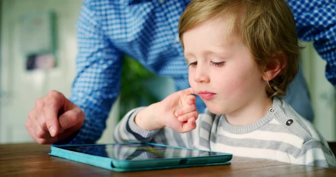 Father Showing Son How To Use Digital Tablet