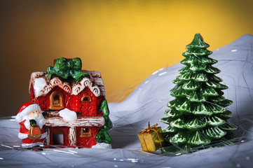 Christmas background - small winter house and Christmas tree on a yellow shining background 