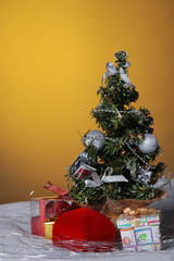 Christmas background - small winter house and Christmas tree on a yellow shining background 