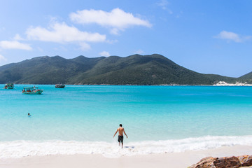 Homem entrando no mar azul em Arraial do Cabo - Rio de Janeiro