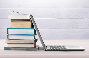Stack of books with laptop on table