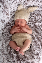 Baby in schönem Hasenkostüm liegt im Bett