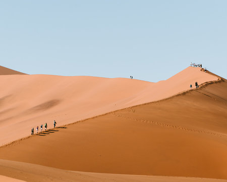 People walking along a sand dune