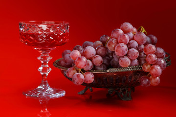 Vase with grapes and a glass of red wine
