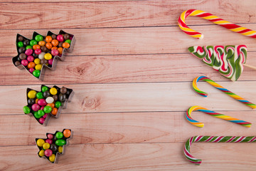 Frame made of holiday Christmas, new year sweets, candy canes laying on wooden background. Copy space for text