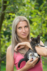 Girl holding a black cat with a blurred background