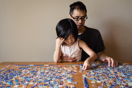 Father and daughter working on a jigsaw puzzle together