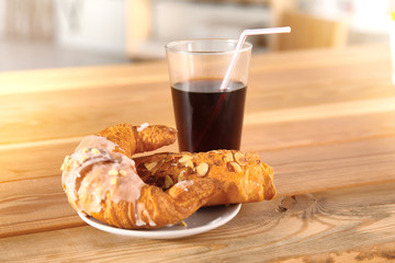 Croissant and a drink in a glass on a wooden table