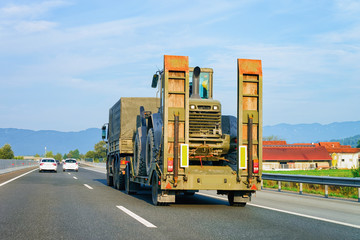 Truck trailer transporter and hauler carrying tractor on road Slovenia