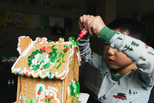Young boy decorating a gingerbread house