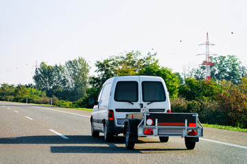 Fototapeta na wymiar Mini van carrying trailer in asphalt road in Slovenia