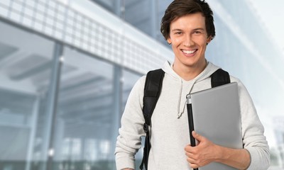 Male student with laptop on background