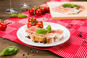 Fototapeta na wymiar Plentiful table with bread, ham, white wine, tomatoes and ingredients