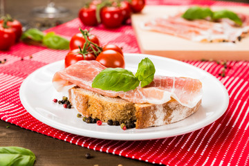 Plentiful table with bread, ham, white wine, tomatoes and ingredients