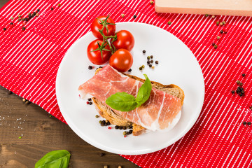Plentiful table with bread, ham, white wine, tomatoes and ingredients