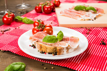 Plentiful table with bread, ham, white wine, tomatoes and ingredients