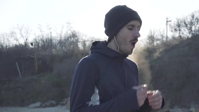 Young male runner training outdoors in the cold weather, athlete workout on the autumn beach